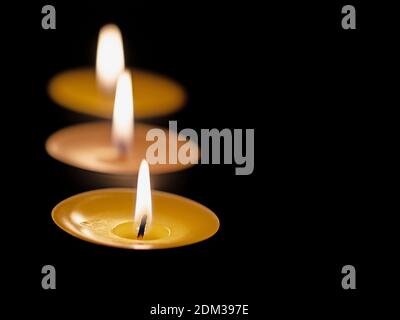 Three tea lights against a black background Stock Photo