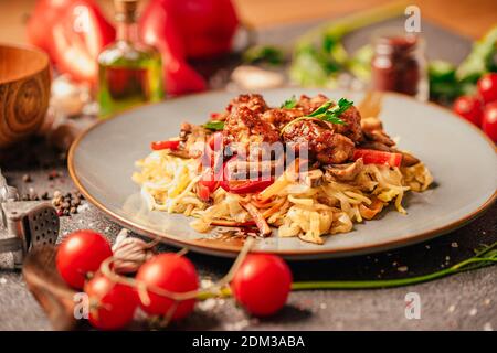 Asian style colorful vegetable and meat stir fry with noodles in spicy sauce.Teriyaki Mongolian beef over udon noodles.Soy sauce beef stew with pepper Stock Photo