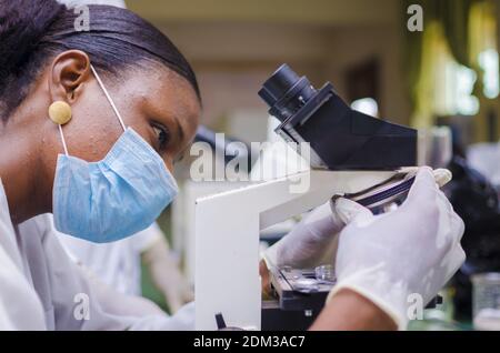 A young African scientist looking through a microscope in the laboratory Stock Photo