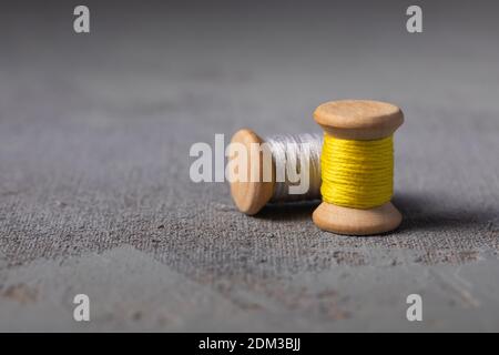 Trendy Illuminating Yellow and Ultimate grey colored threads wooden bobbins for stitching on concrete background Stock Photo