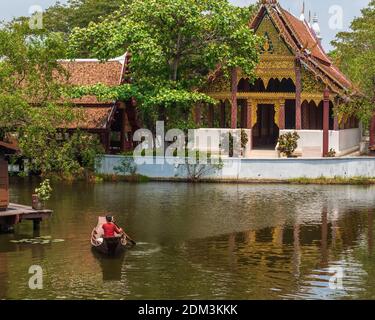 Laem Chabang, Thailand -- March 16, 2016 -- Woman paddles a small boat along a water market in Thailand. Editorial Use Only. Stock Photo