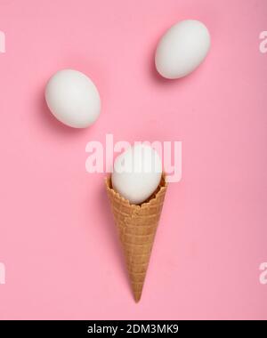 White chicken eggs in a waffle horn on a pink background, top view, flat lay, minimalist trend Stock Photo