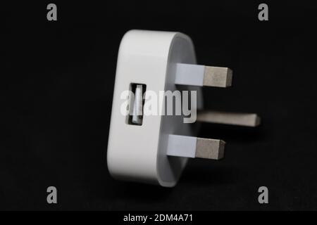 a White 3 pin UK mains electric charging plug with a standard USB slot for connection of a charging cable Stock Photo