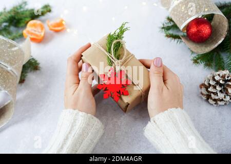 Hands of woman holding Christmas gift box with winter decorations Stock Photo