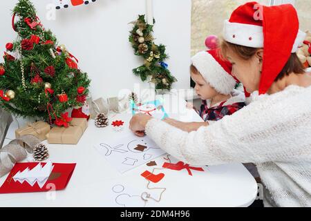 Family making seasonal greeting cards together at christmas time, grandmother with granddaughter at home Stock Photo