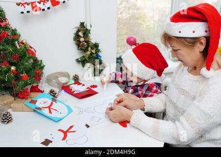 Family making seasonal greeting cards together at christmas time, grandmother with granddaughter at home Stock Photo