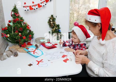 Family making seasonal greeting cards together at christmas time, grandmother with granddaughter at home Stock Photo