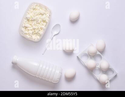 A bottle of yogurt, white eggs in a plastic tray, cottage cheese layout on a white background, top view Stock Photo