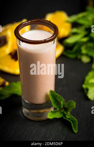 Alcohol cocktail in shot glass with chocolate liqueur, vodka, oranges and mint leaves. Selective focus. Shallow depth of field. Stock Photo