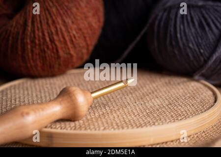 Flat lay composition of punch needle tools on a concrete surface in warm tones. Different sizes of needles, embroidery hoops, scissor and colorful thr Stock Photo