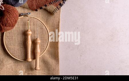 Flat lay composition of punch needle tools on a concrete surface in warm tones. Different sizes of needles, embroidery hoops, scissor and colorful thr Stock Photo