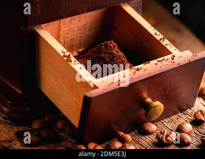Vintage coffee grinder, in dark tones on the rustic wooden background. Old coffee making equipment. Selective focus. Shallow depth of field. Stock Photo