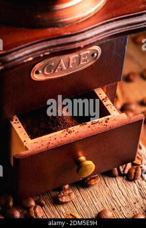 Vintage coffee grinder, in dark tones on the rustic wooden background. Old coffee making equipment. Selective focus. Shallow depth of field. Stock Photo