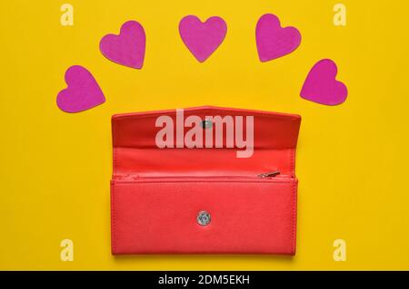 Red leather purse with decorative hearts on a yellow pastel background, concept of love, minimalism Stock Photo