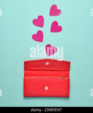 Red leather purse with decorative hearts on a blue pastel background, concept of love, minimalism Stock Photo