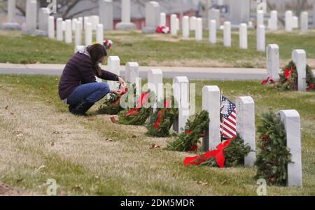 St. Louis, United States. 16th Dec, 2020. A volunteer places a wreath on several graves on National Wreaths Across America Day at Jefferson Barracks National Cemetery in St. Louis on Wednesday, December 16, 2020. Each December on National Wreaths Across America Day, volunteers remember and honor veterans at wreath-laying ceremonies at Arlington National Cemetery, as well as at more than 2,100 additional locations in all 50 U.S. states. Photo by Bill Greenblatt/UPI Credit: UPI/Alamy Live News Stock Photo