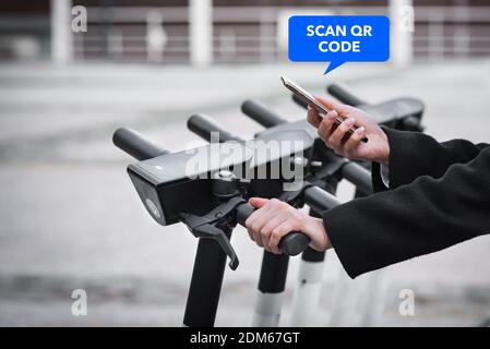 Woman renting an electric scooter with a mobile phone application  Stock Photo