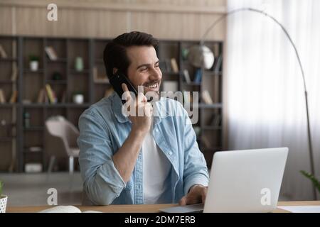 Happy man work on computer talk on smartphone Stock Photo