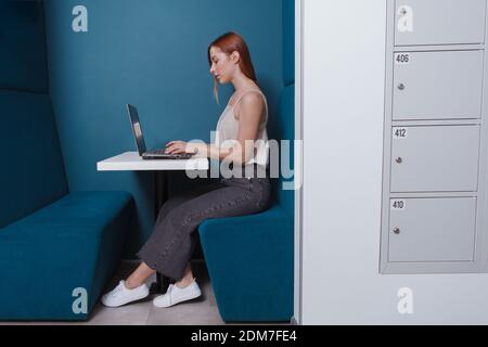 Young woman working on her laptop in a modern co-working office, copy space Stock Photo