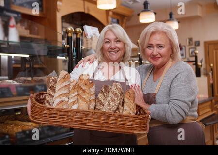 Proud senior mother working with her mature daughter at their bread shop Stock Photo