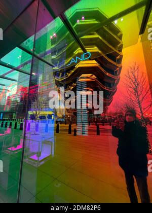 The Vessel, also known as the Hudson Yards Staircase (designed by architect Thomas Heatherwick) in the reflection of a colorful store window. Stock Photo