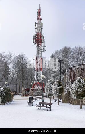 Winter view of red and white communication tower with TV and cellular antennas covered with frost on Parkowa Mountain in Krynica Zdroj, Poland Stock Photo