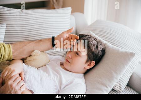 Father caring for sick son lying. Stock Photo