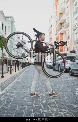 Full length shot of a stylish mature hipster man carrying his bicycle while crossing the road Stock Photo