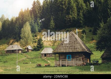 Traditional mountain houses on green field in a old village. Carpathian Mountains, Ukraine