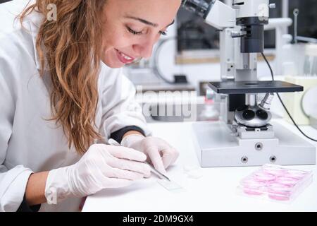 Young female scientist preparing samples to look them through a microscope in a laboratory. Laboratory research concept. Stock Photo