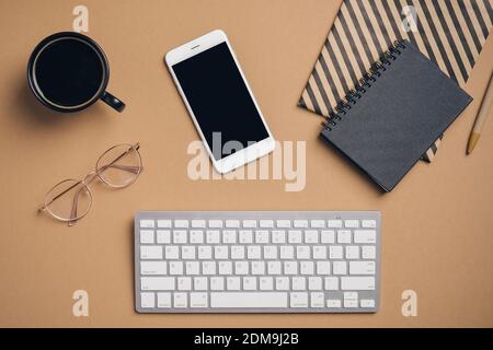 Top view, flat lay keyboard, cup of coffee, paper notebooks, glasses on office desk. Elegant feminine workspace. Business concept Stock Photo