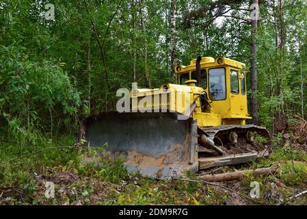 Dozer during clearing forest for construction new road . Yellow Bulldozer at forestry work Earth-moving equipment at road work, land clearing, grading Stock Photo