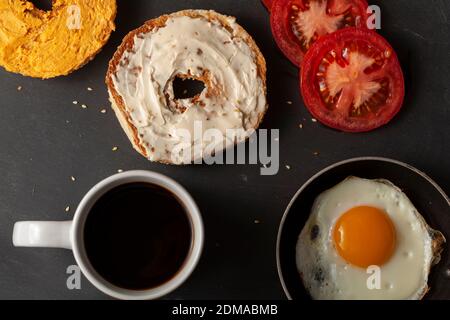 A flat lay breakfast or snack  for one person featuring a sesame bagel toasted and sliced in half with pub cheese and cream  on, slices of tomato, sun Stock Photo