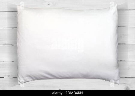 A standard full/queen size pillow resting on a modern white wood background.