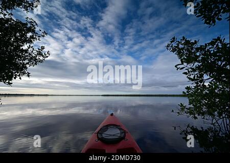 Red kayak on Coot Bay in Everglades National Park, Florida amidst red mangroves under winter cloudscape reflected in tranquil water, Stock Photo