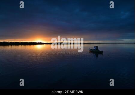 Distant kayaker at sunset on Coot Bay in Everglades National Park, Florida under winter cloudscape reflected in tranquil water. Stock Photo