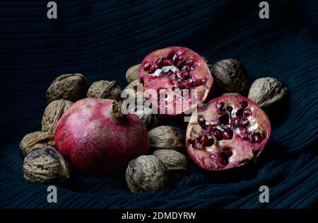 pomegranate whole and open-face with walnuts on a dark green background Stock Photo