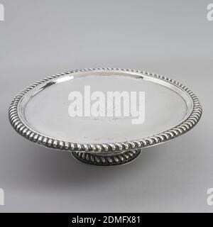Footed Salver, silver, Cylindrical foot, straight platter. Spreading base of foot and rim of top edged with repoussé cording. Engraved in center are three swords in lozenge shield, surrounded by feathers. “M.P.” engraved on back., London, England, 1695–1696, metalwork, Decorative Arts Stock Photo