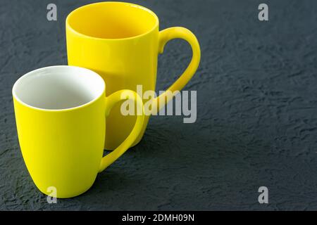 Two yellow cups on gray background. Color of the year 2021 Stock Photo