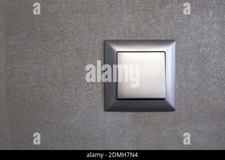 A gray colored light switch on a gray textured wall Stock Photo
