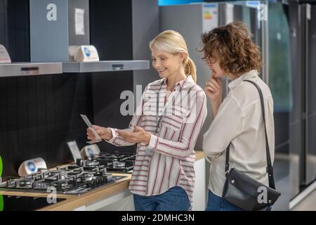 Sales assistant in striped shirt talking to female customer Stock Photo
