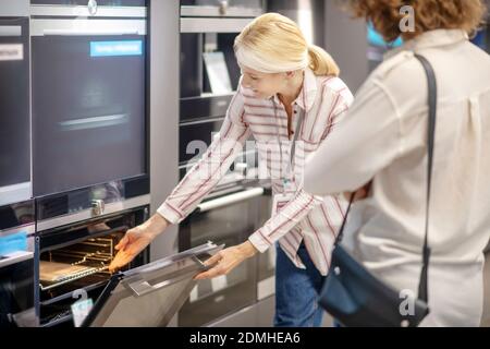Sales assistant in striped shirt showing new ovens to the customer Stock Photo