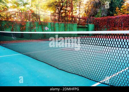 Worn clay or hard surface outdoor tennis court with net Stock Photo