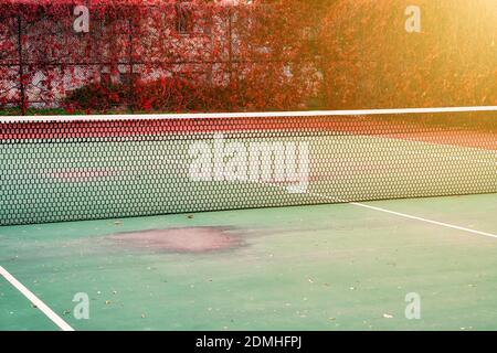 Worn clay or hard surface outdoor tennis court with net Stock Photo