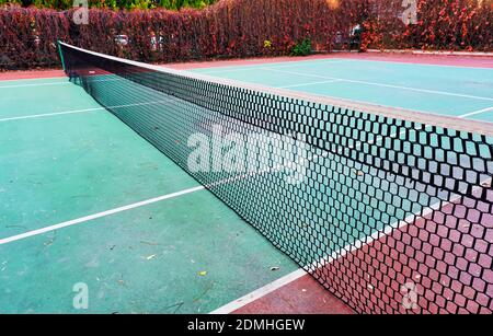 Worn clay or hard surface outdoor tennis court with net Stock Photo