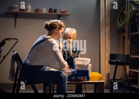the older sister and her younger brother spend time in a pottery workshop, making clay dishes Stock Photo