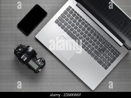 Laptop, frameless phone with white screen, camera on a gray texture surface, top view, copy space Stock Photo