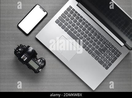 Laptop, frameless phone with white screen, camera on a gray texture surface, top view, copy space Stock Photo
