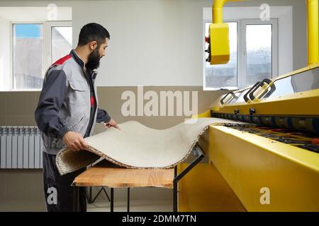 Man operating carpet automatic washing machine in professional laundry service Stock Photo