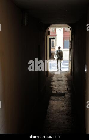Lyon (central-eastern France): silhouette of a man leaving an alleyway (known as “traboule”). Traboules are traditional alleyways between buildings of Stock Photo
